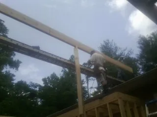 Carpenter setting a ridge beam over a new addition frame — Ice Dam Removal by Roofing Brothers in Dinuba