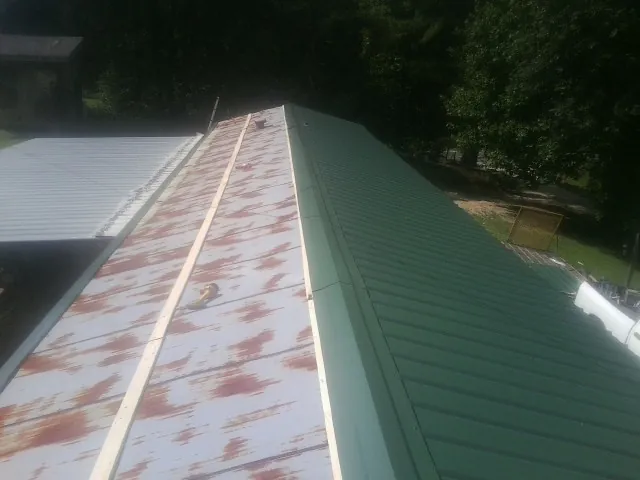 Old rusted panels beside newly installed green metal roofing — Wind Damage Roof Repair by Roofing Brothers in Dinuba