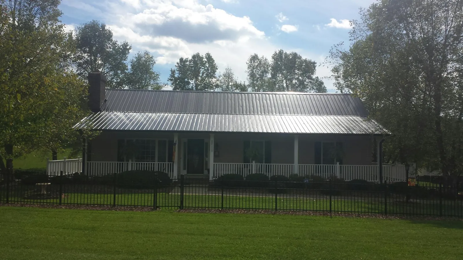 Gray metal roof on a brick ranch with a full width front porch — Gutter Guard Installation work by our crew in Dinuba