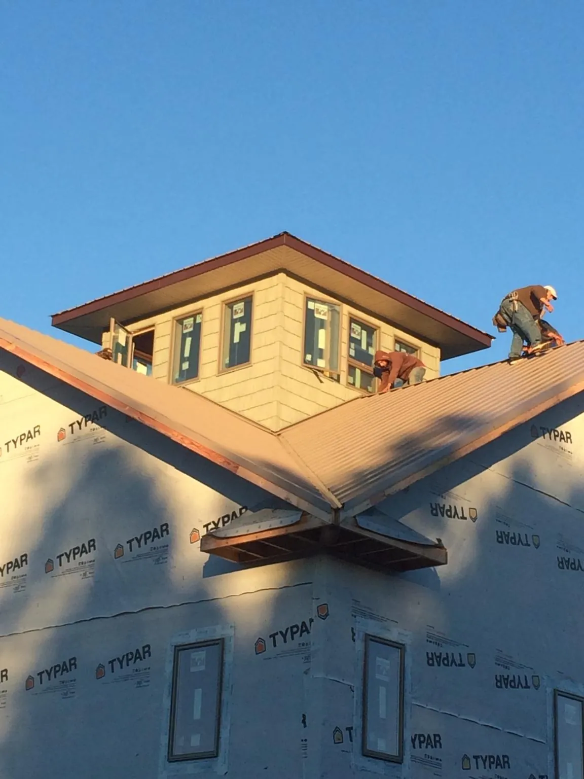 Roofers working around a rooftop cupola on a new metal roof at sunset — Roof Waterproofing in Dinuba by Roofing Brothers